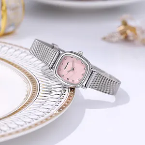 Detail of a square silver mesh watch with a soft pink dial and sparkling diamond markers