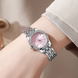 Close-up of a silver ladies watch with a pink dial and crystal-encrusted bezel on a wrist