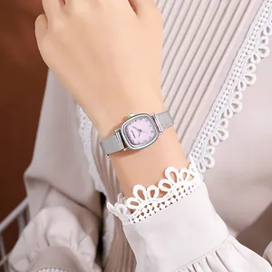Close-up of elegant women's watch with pink square dial and silver mesh band on wrist