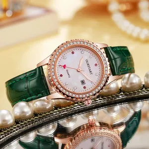 Détail d'une montre femme en or rose avec lunette diamantée et bracelet en cuir vert sur miroir