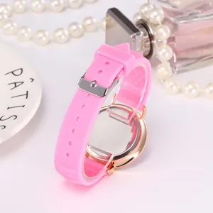 Détail du bracelet en silicone rose et boîtier de montre or rose avec perles et parfum