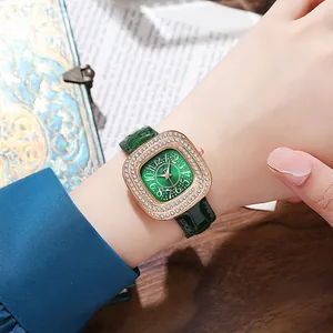 Detail of a square rose gold watch with a diamond bezel and green leather strap on wrist