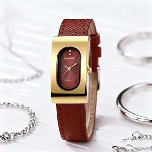Detail of vintage rectangular gold watch with dark red dial and brown leather strap