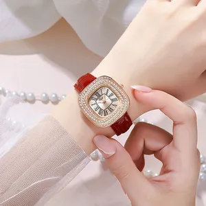 Gros plan d'une montre carrée pour femme avec lunette sertie et bracelet en cuir rouge