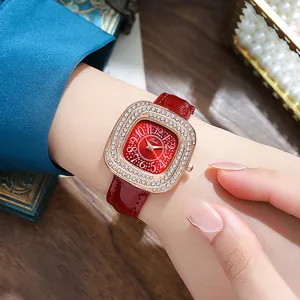 Detail of red leather strap watch with rose gold diamond case on a model's wrist
