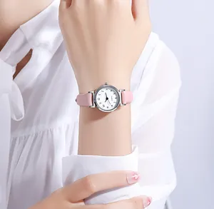 Detalle de correa de cuero rosa y reloj de cuarzo plateado en muñeca femenina elegante