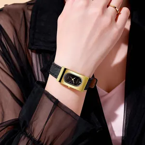 Close-up of vintage rectangular gold watch with black leather strap on female wrist