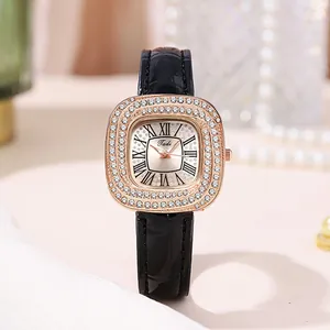 Détail d'une montre à quartz or rose avec lunette en strass et bracelet cuir noir