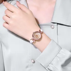 Primo piano di un orologio in oro rosa con quadrante champagne e cinturino bianco