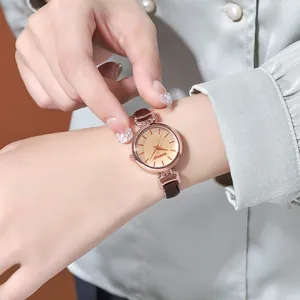 Primo piano di un orologio al quarzo da donna dorato con cinturino in pelle marrone