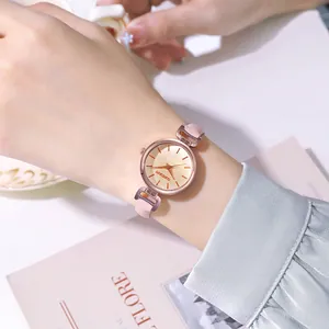 Dettaglio di elegante orologio da donna con quadrante champagne e cinturino rosa