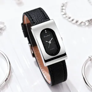 Macro detail of a rectangular silver watch case with a black leather strap on a textured surface
