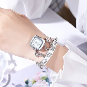 Détail d'une montre carrée argentée pour femme et d'un bracelet à breloques LOVE