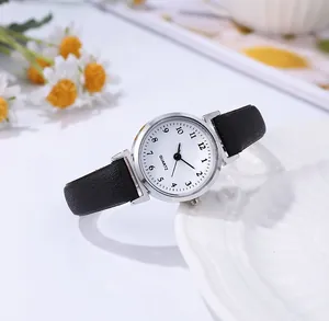 Primer plano de un reloj de cuarzo minimalista para mujer con correa negra y esfera blanca