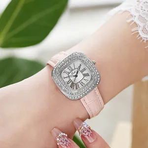 Détail d'une montre carrée argentée ornée de strass avec un bracelet en cuir rose