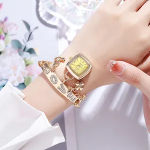 Détail d'une montre à quartz dorée et d'un bracelet à breloques avec gravure LOVE