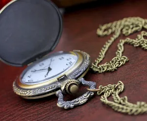 Macro detail of antique bronze pocket watch with floral carvings and a white dial