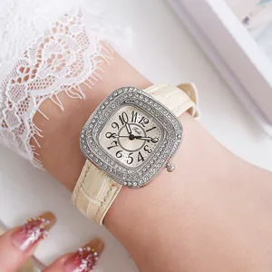 Close-up of elegant square watch with sparkling rhinestones and beige leather strap