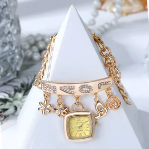 Gros plan de la montre bracelet dorée avec barre de diamants et breloques