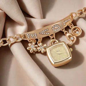 Détail macro d'une montre à quartz or champagne avec breloques cœur et lettrage LOVE