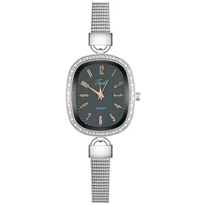 Detailed close-up of oval silver watch with rhinestone bezel and mesh bracelet strap