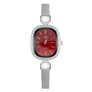 Detail of elegant silver mesh strap watch with red sunburst dial and rhinestone bezel