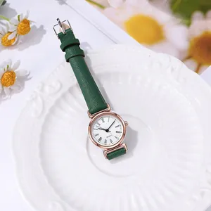 Détail d'une montre vintage pour femme avec bracelet en cuir vert dans un plat en céramique