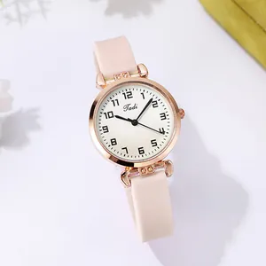 Close-up of minimalist rose gold watch with pink silicone strap and Tadi logo dial