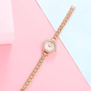 Detailed macro of rose gold watch featuring a diamond bezel and white dial on a chain strap
