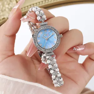 Détail d'une montre argentée avec cadran en nacre bleu clair et bracelet de perles chic