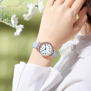 Close-up of a minimalist quartz watch with blue strap and rose gold case on a wrist