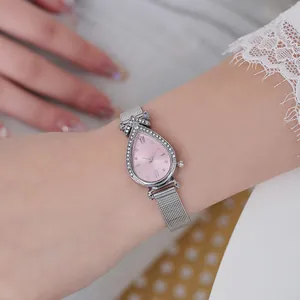 Detail of teardrop quartz watch with pink dial and silver mesh strap on female wrist
