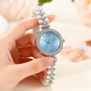 Détail de la montre argentée avec cadran nacré bleu et bracelet en perles élégant