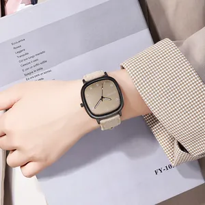 Minimalist square quartz watch with beige leather strap worn against a lifestyle backdrop