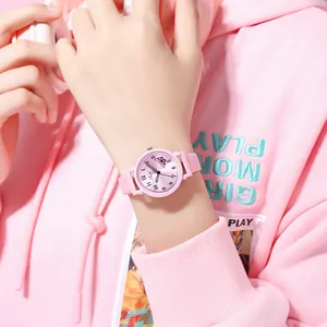 Pink quartz watch with butterfly pattern dial worn by a student in a cozy setting