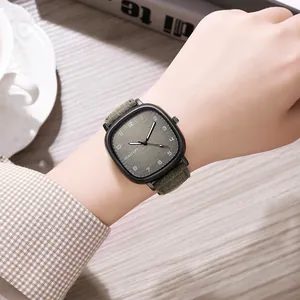 Close-up of a square quartz watch with a green suede strap on a wrist in a lifestyle setting