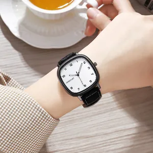Detail of square quartz watch with brushed white dial and black fabric strap on wrist