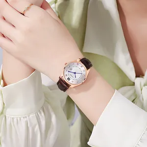 Detail of rose gold watch with sunray dial, blue hands, and brown leather strap