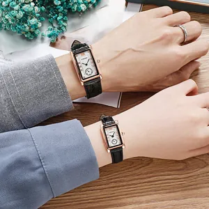 Detail showing a couple wearing matching square watches with leather straps on a desk