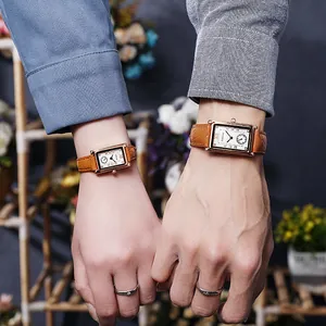 Close-up of couple matching rectangular quartz watches with brown leather straps