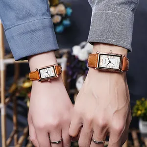Close-up of couple wearing matching rose gold square watches with brown leather straps