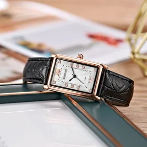 Macro shot of rectangular rose gold watch with black leather strap and textured dial