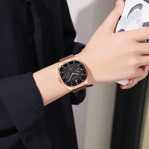 Detailopname van een roségouden vierkant horloge met bruine siliconen band om de pols