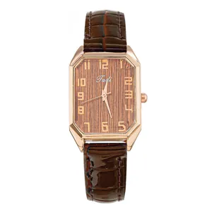 Detalle de reloj rectangular oro rosa con esfera de textura madera y correa de cuero