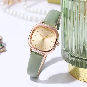 Detail of rose gold square watch case with gold dial and green leather strap in lifestyle setting