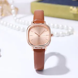 Macro detail of rose gold watch face with sunray dial and brown leather strap