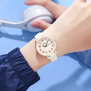 Close-up of minimalist women's watch with white leather strap on a blue background