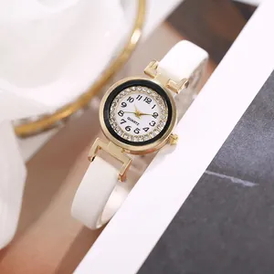 Detailed close-up of a stylish white leather watch band and gold diamond-encrusted dial