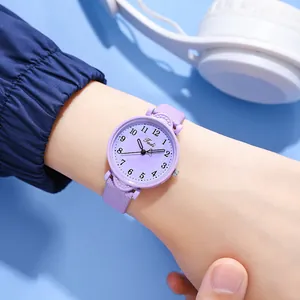Close-up of a lilac quartz watch with Arabic numerals on a model's wrist with blue background