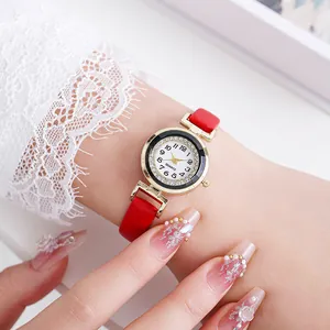 Detailed close-up of a stylish gold watch with red leather strap and diamond-set bezel